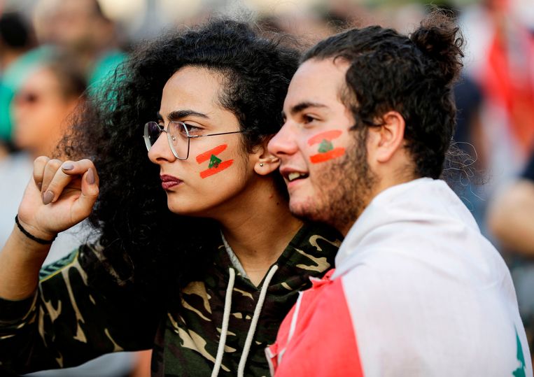 Demonstranten met de Libanese vlag op hun gezicht geschminkt. Beeld AFP