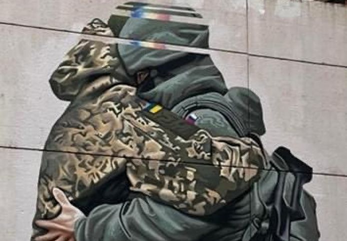 Een beeld van de muurschildering die toont hoe een Oekraïense en een Russische soldaat knuffelen.