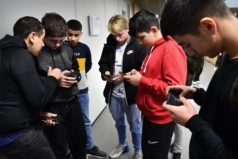 Leerlingen van het Melanchthon zitten in de pauze op hun smartphone.  Beeld Marcel van den Bergh / de Volkskrant