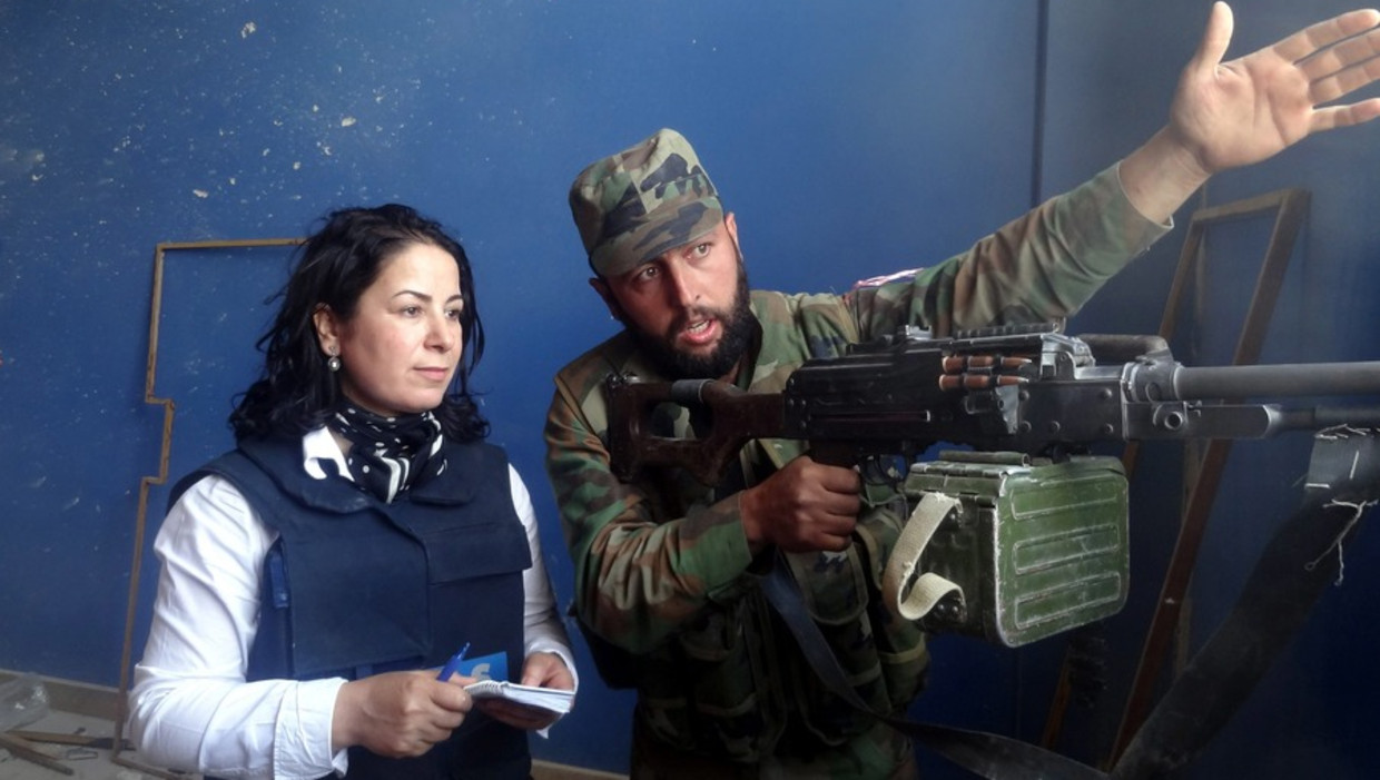 Een Syrische soldaat spreekt met een journalist. Onbekend is wie de journalist is, of voor welk medium ze werkt. De foto is gepubliceerd door de Syrische staatstelevisie. Beeld epa