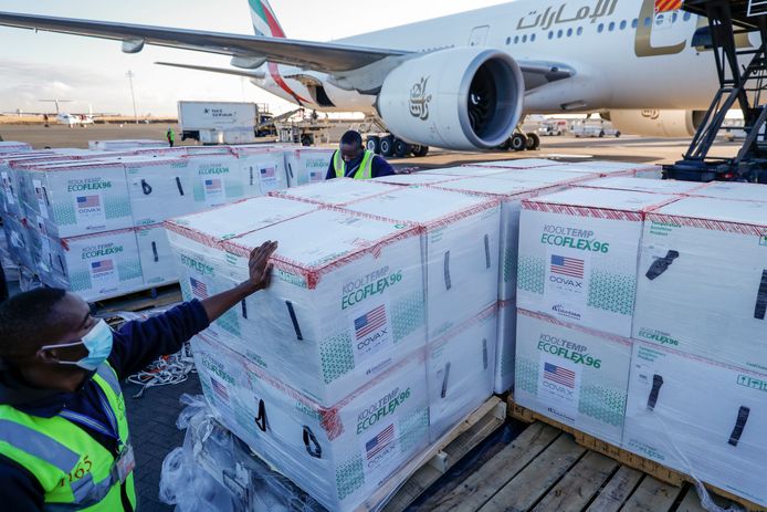 Een luchthavenmedewerker staat naast een grote lading vaccins die toekomt in Afrika