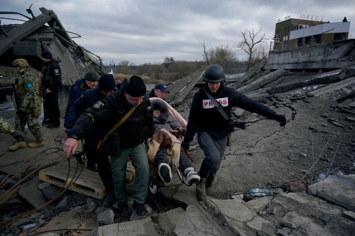 Een vrouw wordt weggebracht na een Russisch bombardement in Romanivka, Oekraïne. Beeld REUTERS