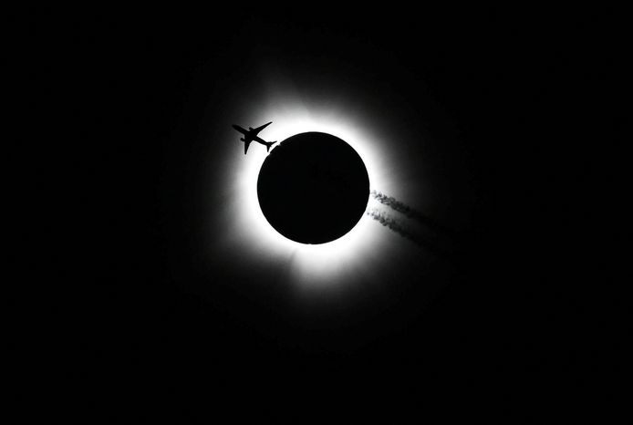 Een vliegtuig vliegt voor de zonsverduistering langs.