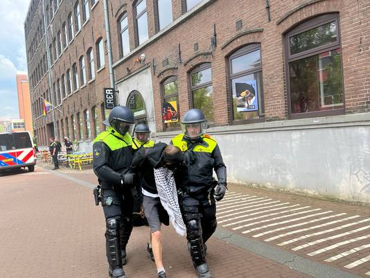 De politie neemt een demonstrant mee in Amsterdam. 

