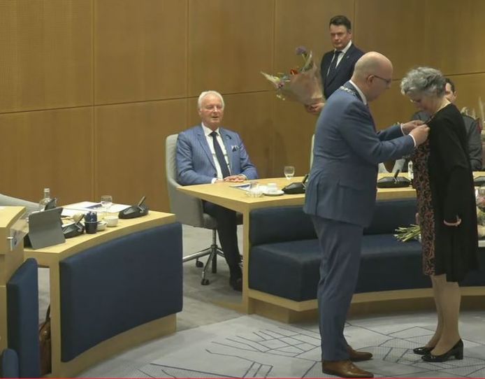 Burgemeester Jack Mikkers speldt Annemarie Hoog Antink de versierselen op die behoren bij een koninklijke onderscheiding.