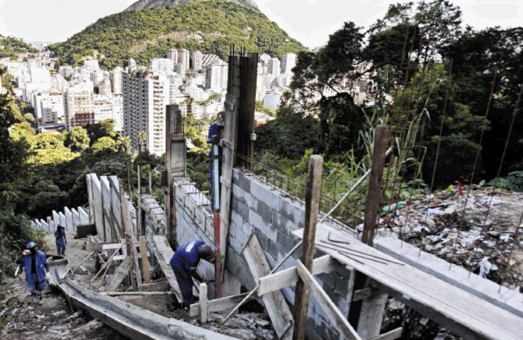 De muur in aanbouw langs de sloppenwijk Santa Marta ten zuiden van Rio de Janeiro. (FOTO AFP) Beeld 