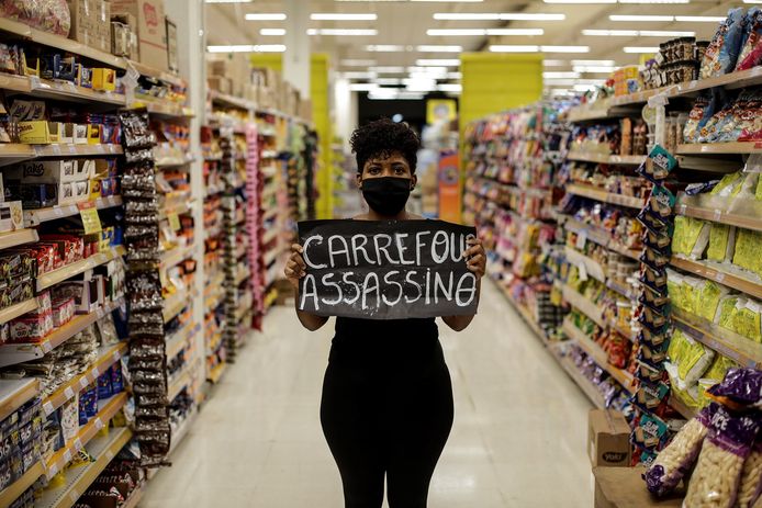 Een vrouw in een Carrefour-filiaal in Rio de Janeiro met een spandoek waarop de tekst 'Carrefour moordenaar' geschreven staat.