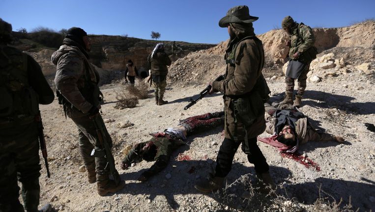 Door Turkije gesteunde rebellen staan in het noorden van Al-Bab bij de lichamen van strijders die volgens hen tot Islamitische Staat behoorden Beeld reuters
