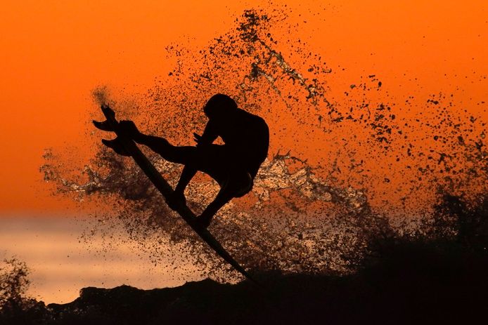 Een surfer tijdens zonsondergang in actie in Californië.