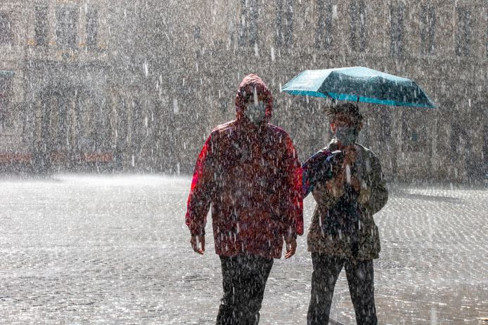 Twee wandelaars lopen in de regen op een verlaten Grote Markt in Brussel.