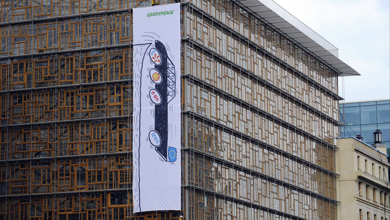 Spandoek van Greenpeace met daarop een zwarte dienstauto van de Europese Unie die een afgrond inrijdt. Beeld afp