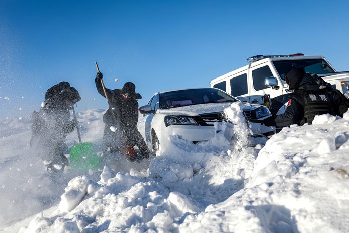 Politiemannen helpen bij het uitgraven van een auto uit de sneeuw.