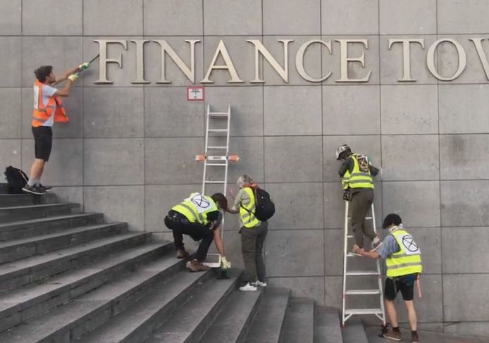 Leden van Extinction Rebellion verwijderen de letters van de Financietoren in Brussel.