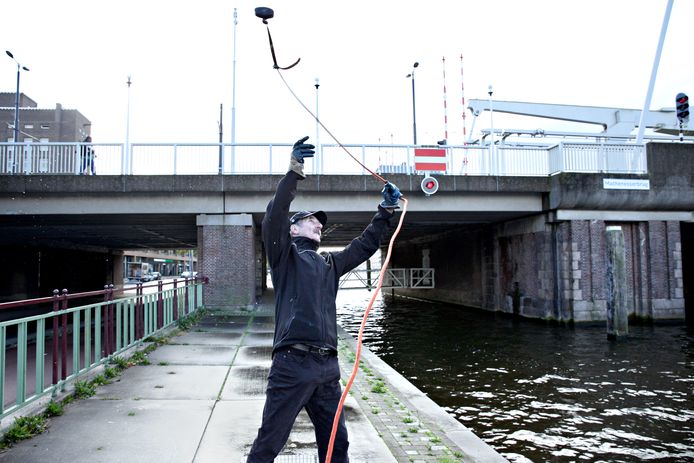 Ron Hagen gooit met regelmaat  zijn touw met magneet in het water van de Schie: „Je weet nooit wat er naar boven komt.’’