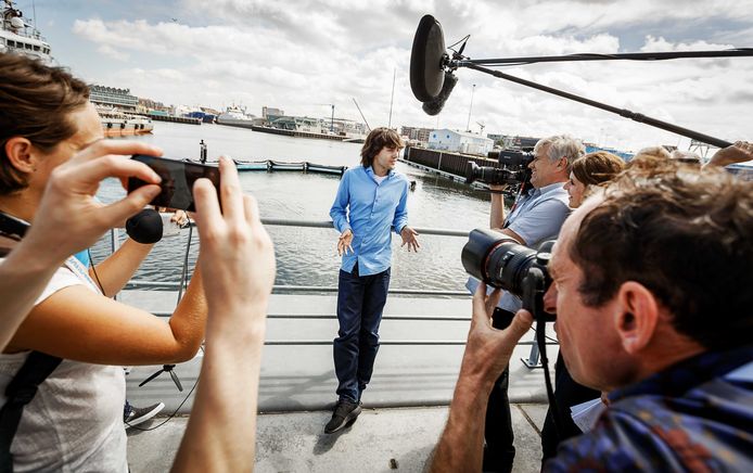Boyan Slat staat de pers te woord met achter zich het Noordzee-prototype van The Ocean Cleanup.