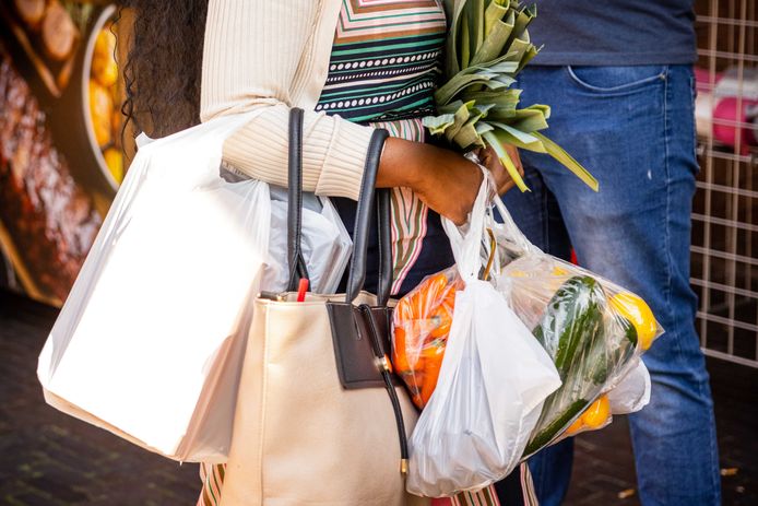 Een vrouw draagt assen met boodschappen. Maaltijdcheques spelen een belangrijke rol in het maandelijkse voedingsbudget van werknemers.
