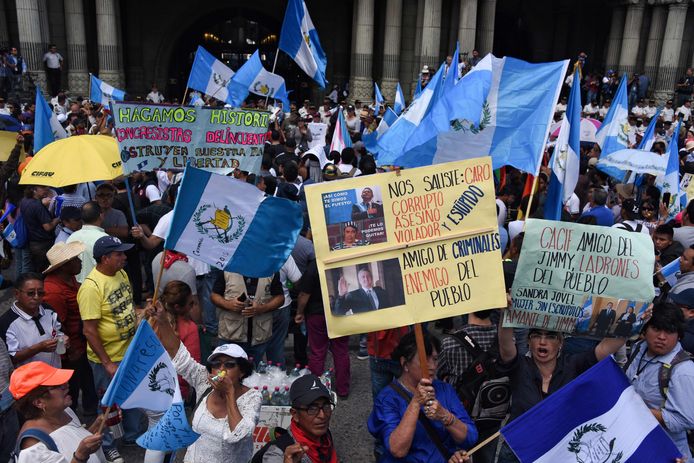 Betogers demonstreren in het centrum van Guatemala-Stad tegen president Jimmy Morales. Een vrouw houdt een bord omhoog waarop naast een foto van Morales onder meer te lezen valt: 'Vriend van criminelen, vijand van het volk'.