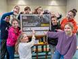 Elise Zevenbergen (10) schrijft namens de Kinderraad van de ABS het bedrag op dat haar school heeft ingezameld voor de slachtoffers van de aardbevingen in Turkije en Syrië. Rechts (oranje trui) staat adjunct-directeur Tamara Vliegenthart.