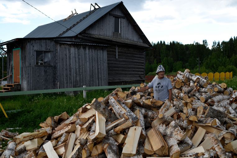 Een inwoner van het dorp Kiltovo bij zijn voorraad hout, de belangrijkste brandstof in de regio.  Beeld Yuri Kozyrev / Noor