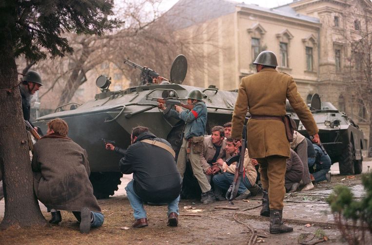 24 december 1989: anti-communistische activisten schuilen samen met Roemeense militairen achter een tank in Boedapest.  Beeld AFP