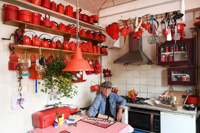 Peter de Krom in zijn keuken, omringd door 295 stuks rode emaillen huishoudspulletjes. Sowieso komt de kleur rood veel in zijn woning terug.