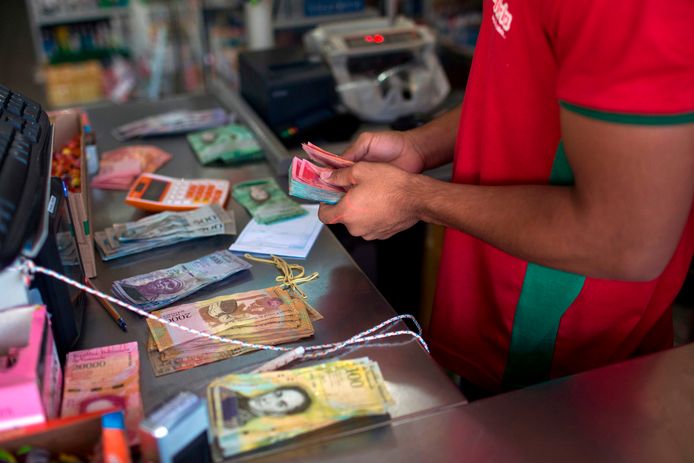 Een Braziliaanse winkelier telt Venezolaans geld aan de grens.
