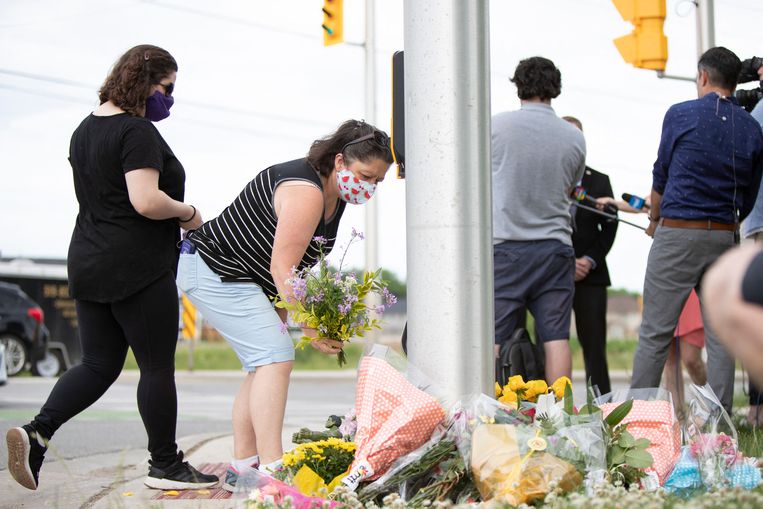 Mensen leggen bloemen neer op de plek waar het gezin opzettelijk werd doodgereden. Beeld AFP