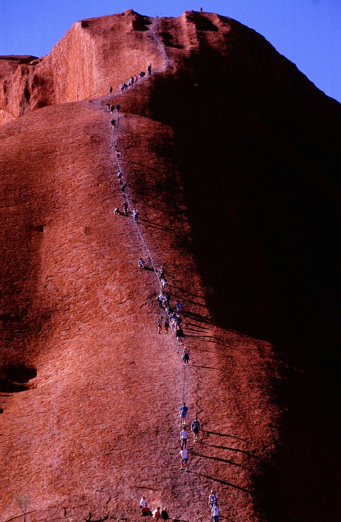 FILE PHOTO - Tourists climb one of Australia's top tourist attractions, the towering red monolith of Uluru, formerly known as Ayers Rock, at sunset in the Australian outback, July, 1997.  REUTERS/David Gray/File photo