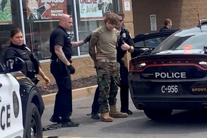 Een verdachte in camouflage-kleding wordt door de politie afgevoerd.