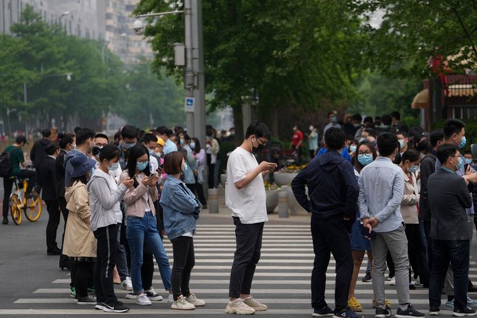 Bewoners en kantoormedewerkers in de wachtrij bij een testlocatie in Chaoyang.