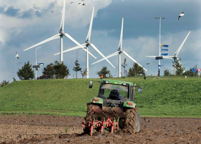 Een boer ploegt zijn akker met op de achtergrond de windmolens langs de A15 bij Echteld. Wellicht ziet de omgeving van Niftrik er over een paar jaar ook zo uit.
