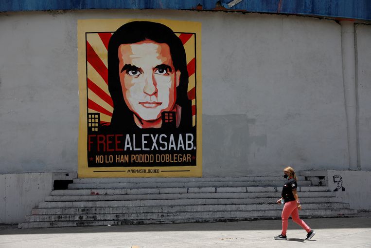 Een vrouw loopt langs een poster met daarop een oproep om de vrijlating van de Colombiaanse zakenman Alex Saab. Beeld REUTERS