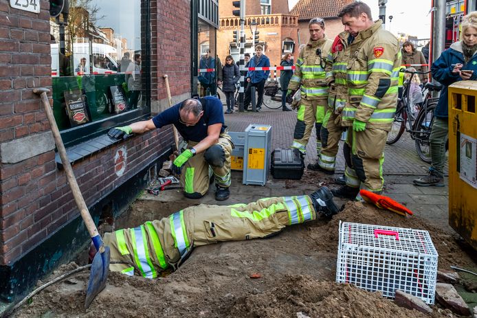 De brandweer probeert een opening te maken om zo de ruimte in te kunnen kruipen.
