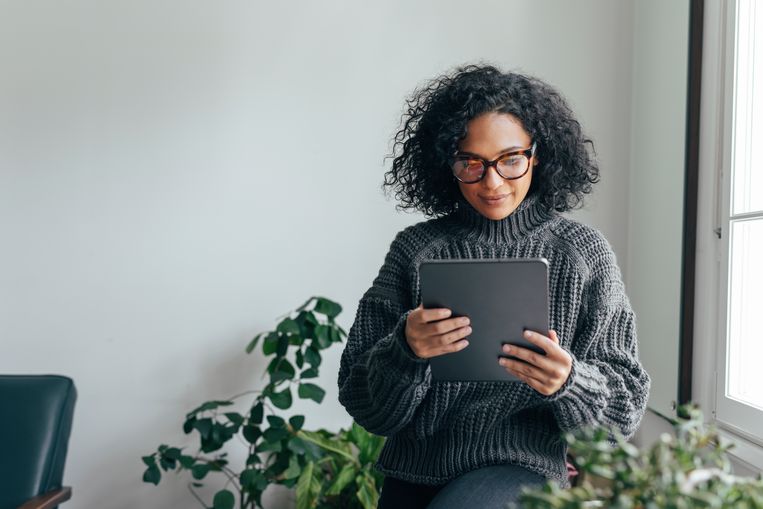 Woman wearing glasses watching something on her digital tablet (copy space). Beeld Getty Images