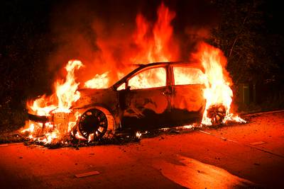 Auto in brand gestoken op grasveld met bomen in Riethoven, brandweer bereikt vuur met moeite