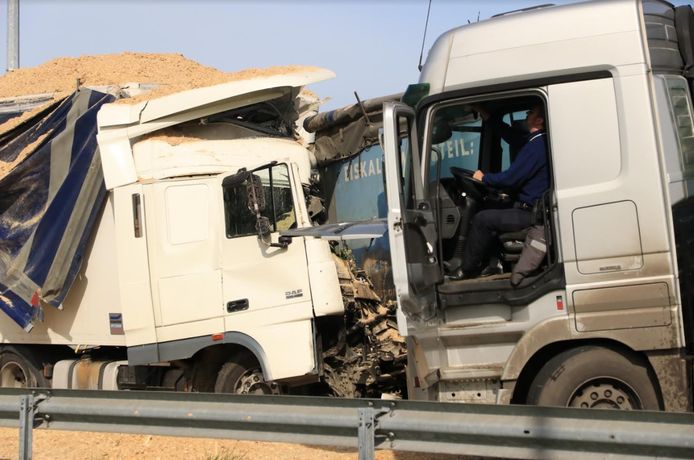 Een agent (rechts) doet vaststellingen in de aangereden Duitse vrachtwagen.  Door de klap draaide de truck en kwam zo tegenover de aanrijdende Nederlandse vrachtwagen te staan.