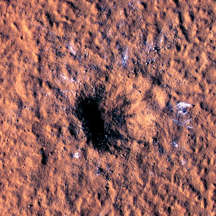 Brokken ijs zijn te zien rond de buitenkant van de krater veroorzaakt door een meteoroïde die op 24 december neerstortte op Mars