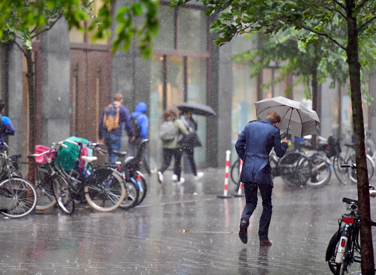 Een voorbijganger loopt door een stevige regenbui op de Turfmarkt in Utrecht. Beeld ANP