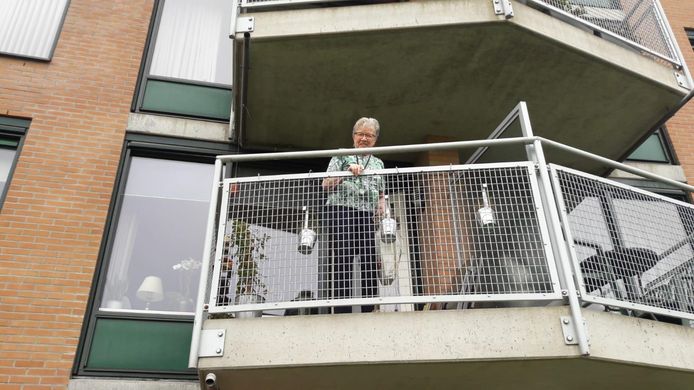 Anna Hartman (86) van De Posten hengelt via haar balkon spulletjes binnen van familie die beneden staat. Het huis zit op slot vanwege corona.