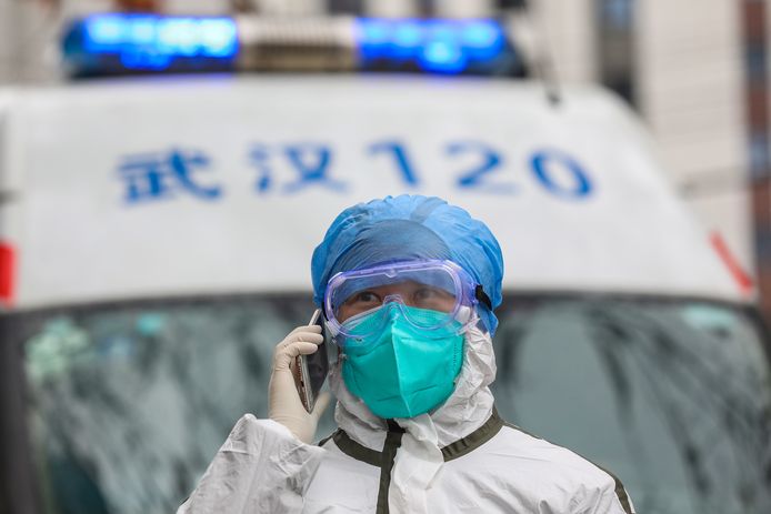 Een verpleger loopt naast een ambulance in Wuhan.