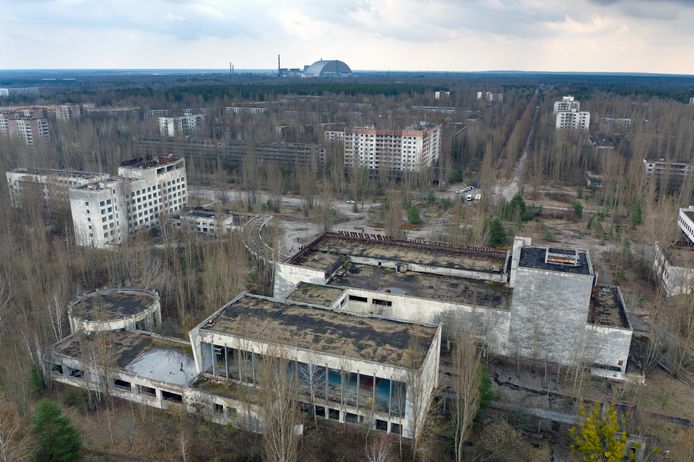 Spookstad Pripyat met op de achtergrond de sarcofaag die de kernreactor in Tsjernobyl bedekt.