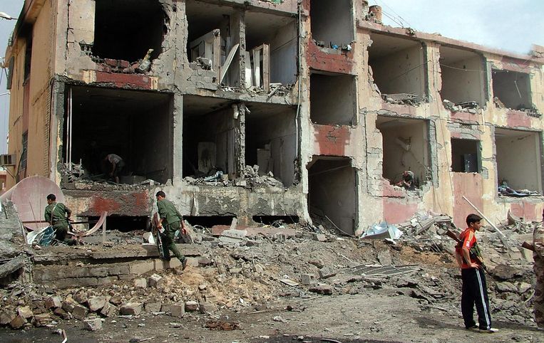 Syrische politiemannen bij verwoeste gebouwen in Deir Al-Zour in 2012. Beeld EPA
