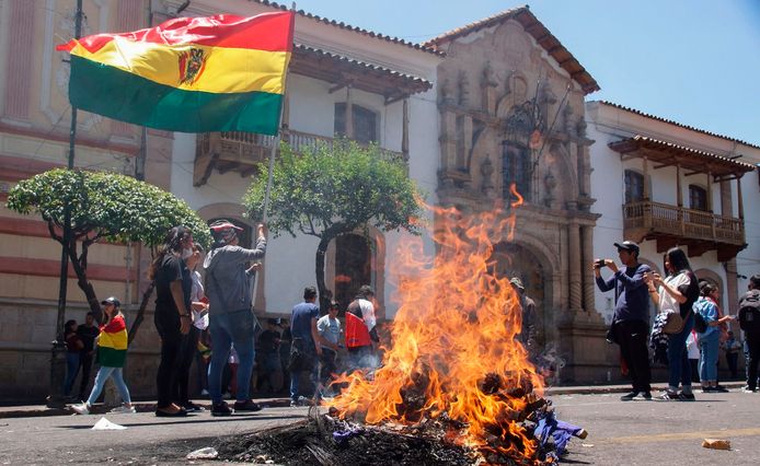 Tegenstanders van president Evo Morales stichten brand op straat en houden de Boliviaanse vlag omhoog in Sucre.