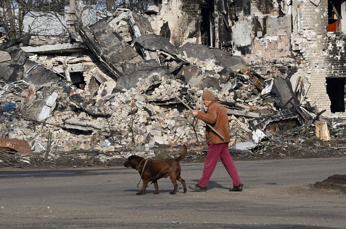 Illustratiebeeld: een man wandelt met zijn hond voorbij verwoeste gebouwen in het Oekraïense stadje Volnovakha, in Donetsk.