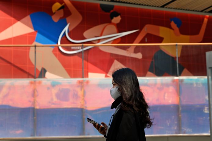 Een vrouw wandelt voorbij een Nike-winkel in de Chinese hoofdstad Peking.