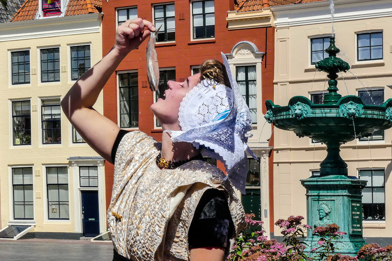 Marije van den Berge hapt gekleed in klederdracht in Vlissingen een mals harinkje naar binnen.