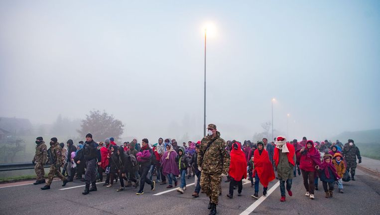 Soldaten begeleiden vluchtelingen op een weg bij Sentilj, Slovenië om de grens over te steken. Beeld AFP
