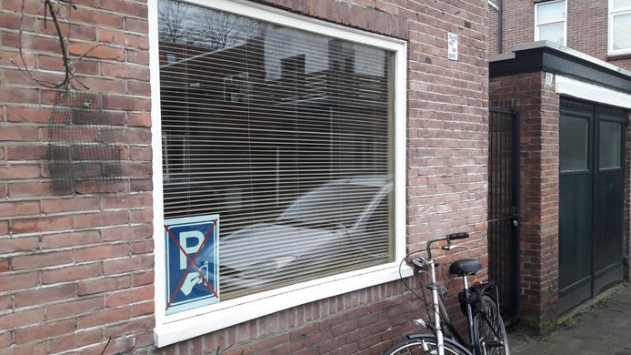 Protest met posters voor het raam tegen betaald parkeren in Breda.