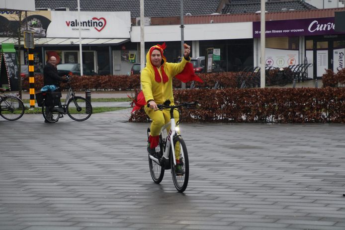 Wijkagent Robbie Steenbeek in kippenpak op een politiefiets.