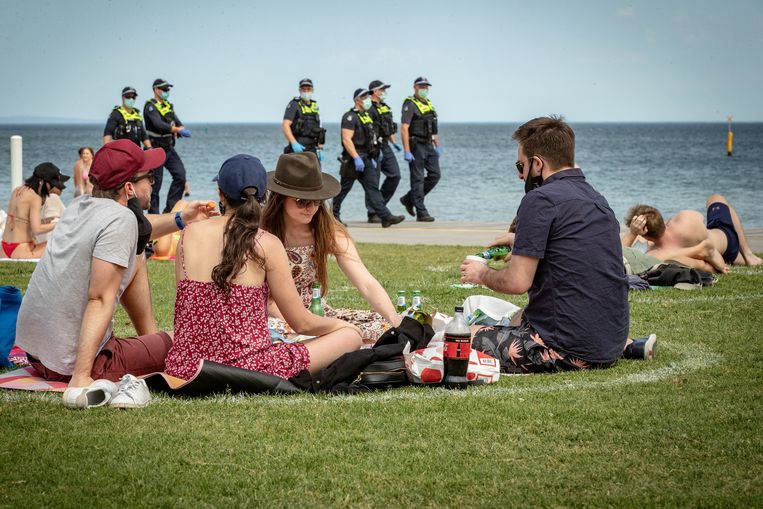 Badgasten picknicken onder het oog van de politie op St. Kilda-strand in Melbourne.  Beeld Darrian Traynor / Getty Images